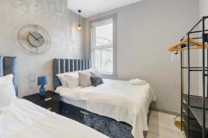a bedroom with two beds and a clock on the wall at Wembley Luxury 3 Bedroom in London