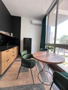 cocina con mesa de madera y sillas verdes en Cactus Apartments en Durrës