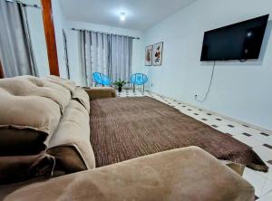 uma sala de estar com um sofá e uma televisão de ecrã plano em Sobrado Com Piscina proximo aeroporto em Campo Grande