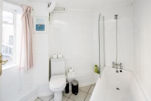 a white bathroom with a toilet and a bath tub at Affordable Flat in Fitzrovia in London