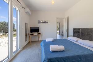 um quarto com uma cama azul e uma grande janela em Manos House - Elegant Modern Escape em Svoronata