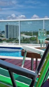 a balcony with a table and chairs and a swimming pool at Cobertura mobiliada Ponta Negra in Natal