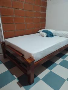 ein Bett in einem Zimmer neben einer Ziegelwand in der Unterkunft CASA KUWA in Mutatá
