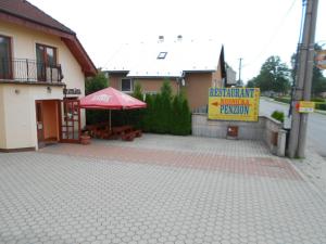 a building with a red umbrella and a sign at Penzion Rosnicka Liesek in Trstená