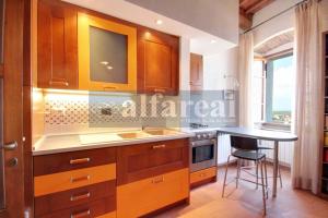 a kitchen with wooden cabinets and a counter top at Fortezza, vista mare nel centro del borgo medioevale in Castiglione della Pescaia