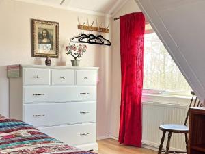 um quarto com uma cómoda e uma janela com cortinas vermelhas em Holiday home KLINTEHAMN IV em Klintehamn