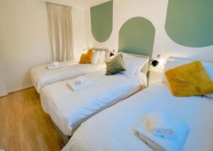 três camas num quarto com branco e verde em 20% Monthly stays - 3 bedrooms @ Homevy Leeds em Beeston Hill