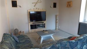 ein Wohnzimmer mit einem Sofa und einem TV in der Unterkunft Gîte Les 3 Cerfs - 3 étoiles in Plainfaing