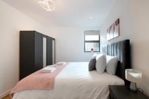 a bedroom with a large bed with a black cabinet at Modern Serviced One Bedroom Flat - Sleeps 4 - Near High Street & Train Station - CR5 London in Coulsdon