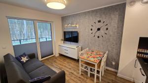 ein Wohnzimmer mit einem Tisch und einer Uhr an der Wand in der Unterkunft Apartament Gdańsk Sobieszewo in Danzig