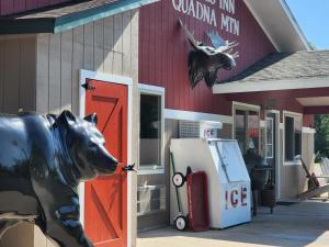 eine Kuhstatue vor einer Tankstelle in der Unterkunft Trails INN Quadna Mountain Motel & RV Park in Hill City