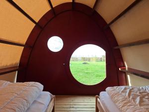 two beds in a room with a round window at Tenthutje BuitenWedde in Wedde
