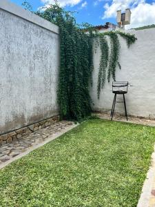 ławka siedząca w trawie obok ściany w obiekcie Ahicito - Casa en Tres Cerritos w mieście Salta