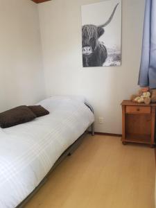 een slaapkamer met een bed en een foto van een stier aan de muur bij De Blauwe Reiger mooi dubbel chalet in de Veluwse bossen in Putten