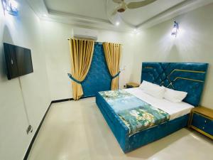 Schlafzimmer mit einem blauen Bett und einem TV in der Unterkunft One Click Guesthouse in Islamabad