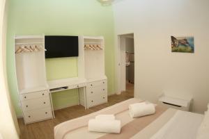 - une chambre blanche avec une télévision et un lit dans l'établissement LUCKY LOFT 16, à La Spezia
