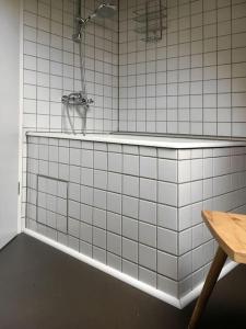 a white tiled bathroom with a tub and a shower at Gemütliches Maisonette-Studio in ehemaliger Scheune in Schwäbisch Gmünd