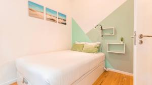 Dormitorio pequeño con cama blanca y 2 cuadros en la pared en M&M Home by LovelyStay en Lisboa