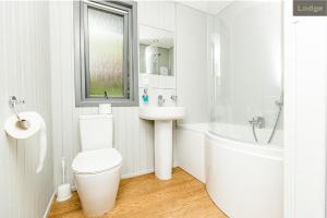 a white bathroom with a toilet and a sink at Firbush Lochside Lodges in Killin