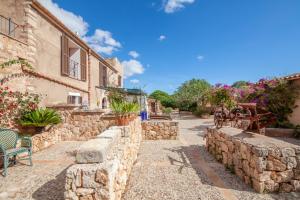 a stone pathway leading to a house with a stone wall at Finca Son Marimon in Santanyi