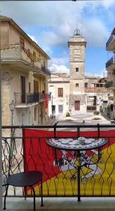 een tafel en stoelen op een balkon met een klokkentoren bij bed & breakfast Acquaviva di Vullo Vincenzo in Acquaviva Platani