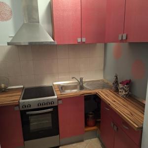 Kaštel Novi的住宿－Mila，厨房配有红色橱柜、炉灶和水槽。