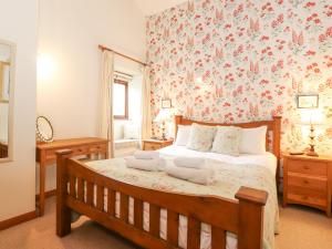 a bedroom with a wooden bed with a floral wallpaper at Roofstones Cottage in Hawes