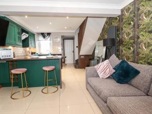 a living room with a couch and a kitchen at Flosh Cottage in Cleator