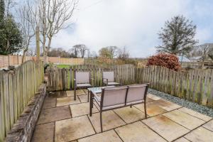 a patio with two chairs and a table and a fence at Flosh Cottage in Cleator