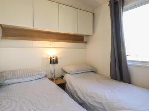 two beds in a small room with a window at Flosh Caravan in Maryport
