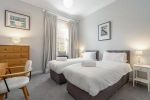 um quarto com 2 camas, uma secretária e uma cadeira em Luxury St Andrews Apartment - 5 mins to Old Course em St. Andrews