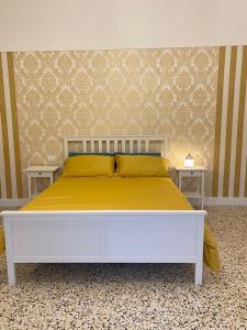 una camera da letto con un letto bianco con lenzuola gialle di La Casa sulla Penisola Sorrentina a Vico Equense