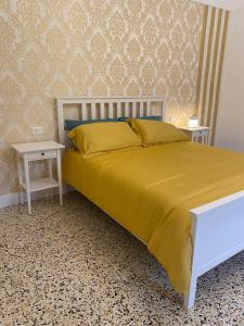 1 dormitorio con 1 cama con colcha amarilla y 2 mesas en La Casa sulla Penisola Sorrentina, en Vico Equense