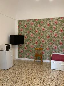 una camera con TV, sedia e carta da parati di La Casa sulla Penisola Sorrentina a Vico Equense