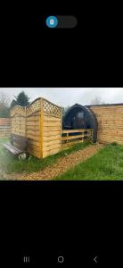 a wooden house with a fence in the grass at New hotub glamping pods in Kinlet