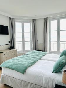 a large bed in a bedroom with windows at Hôtel De La Marine in Arromanches-les-Bains