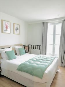 a bedroom with a large white bed with blue pillows at Hôtel De La Marine in Arromanches-les-Bains