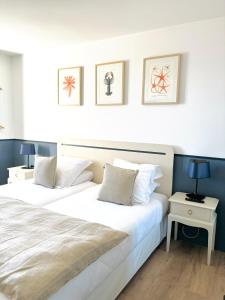 two beds in a room with two tables and two lamps at Hôtel De La Marine in Arromanches-les-Bains