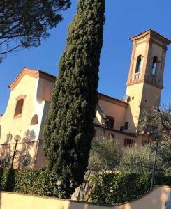 un grand arbre devant un bâtiment avec une tour dans l'établissement Monastero del 600 vista Firenze, à Calenzano