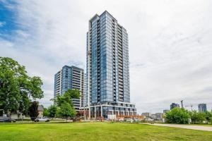 a tall building in a city with a grass field at Upscale 1BR Condo with King Bed and Amazing Cityscape Views in Kitchener