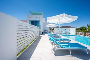 a row of chairs and umbrellas next to a swimming pool at Villa Xenos Ciel in Tigaki