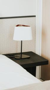 a lamp sitting on a table next to a bed at Hôtel De La Marine in Arromanches-les-Bains