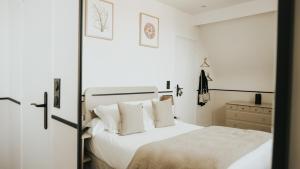 a bedroom with a bed with white sheets and pillows at Hôtel De La Marine in Arromanches-les-Bains
