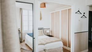 a bedroom with a bed and a mirror at Hôtel De La Marine in Arromanches-les-Bains