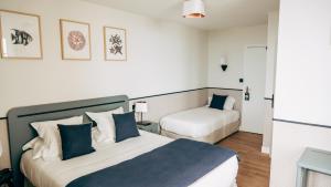 a hotel room with two beds in a room at Hôtel De La Marine in Arromanches-les-Bains