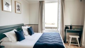 a bedroom with a blue and white bed and a window at Hôtel De La Marine in Arromanches-les-Bains