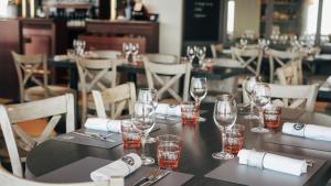 una mesa en un restaurante con copas y servilletas en Hôtel De La Marine, en Arromanches-les-Bains