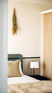a bedroom with a large bed and a lamp at Hôtel De La Marine in Arromanches-les-Bains