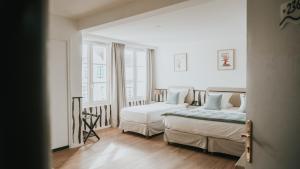 a bedroom with two beds and a large window at Hôtel De La Marine in Arromanches-les-Bains