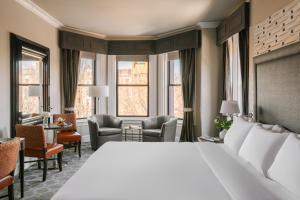 a hotel room with a bed and chairs and windows at No. 284 powered by Sonder in Boston